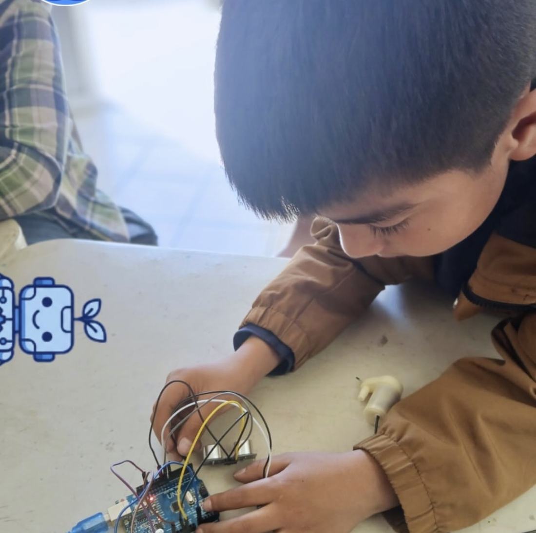 Alumno conectando cables a una placa de desarrollo durante una clase de robótica de Qubiko