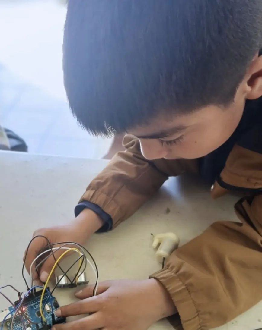 Alumno conectando cables a una placa de desarrollo durante una clase de robótica de Qubiko