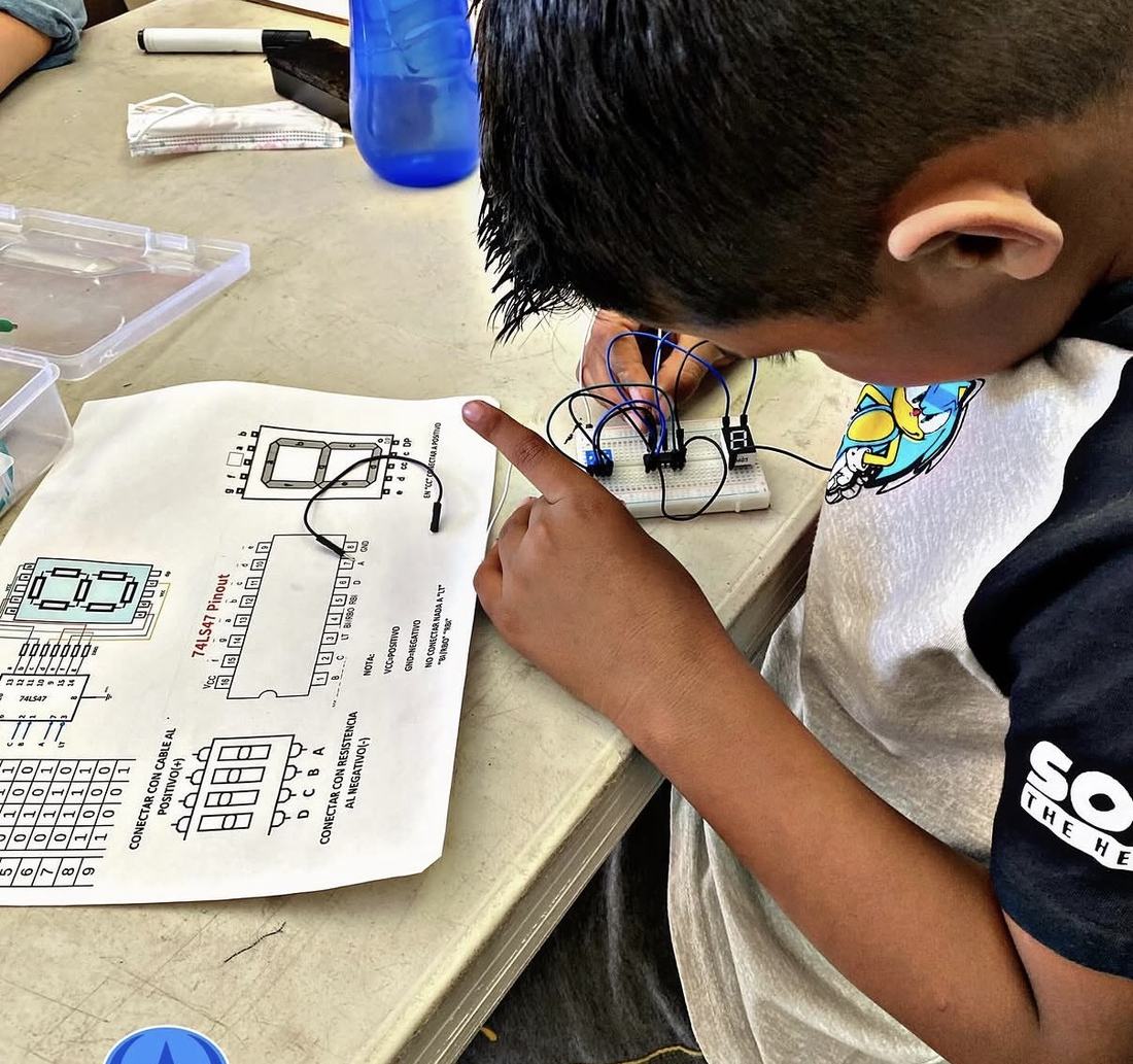 Alumno siguiendo la guía impresa del kit de robótica de Qubiko mientras arma su circuito
