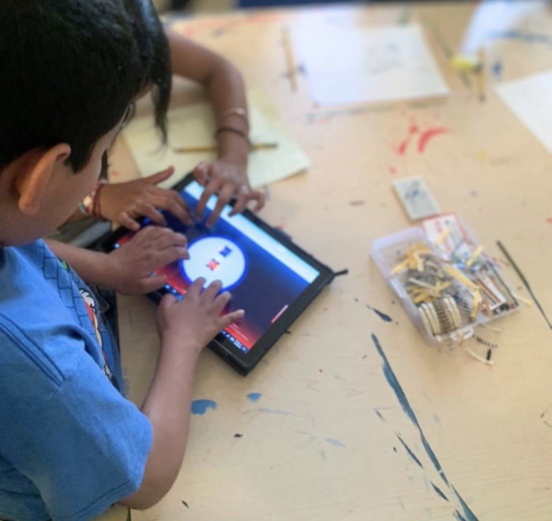 Alumno usando el simulador de Qubiko desde una tablet, junto a la caja de componentes del kit