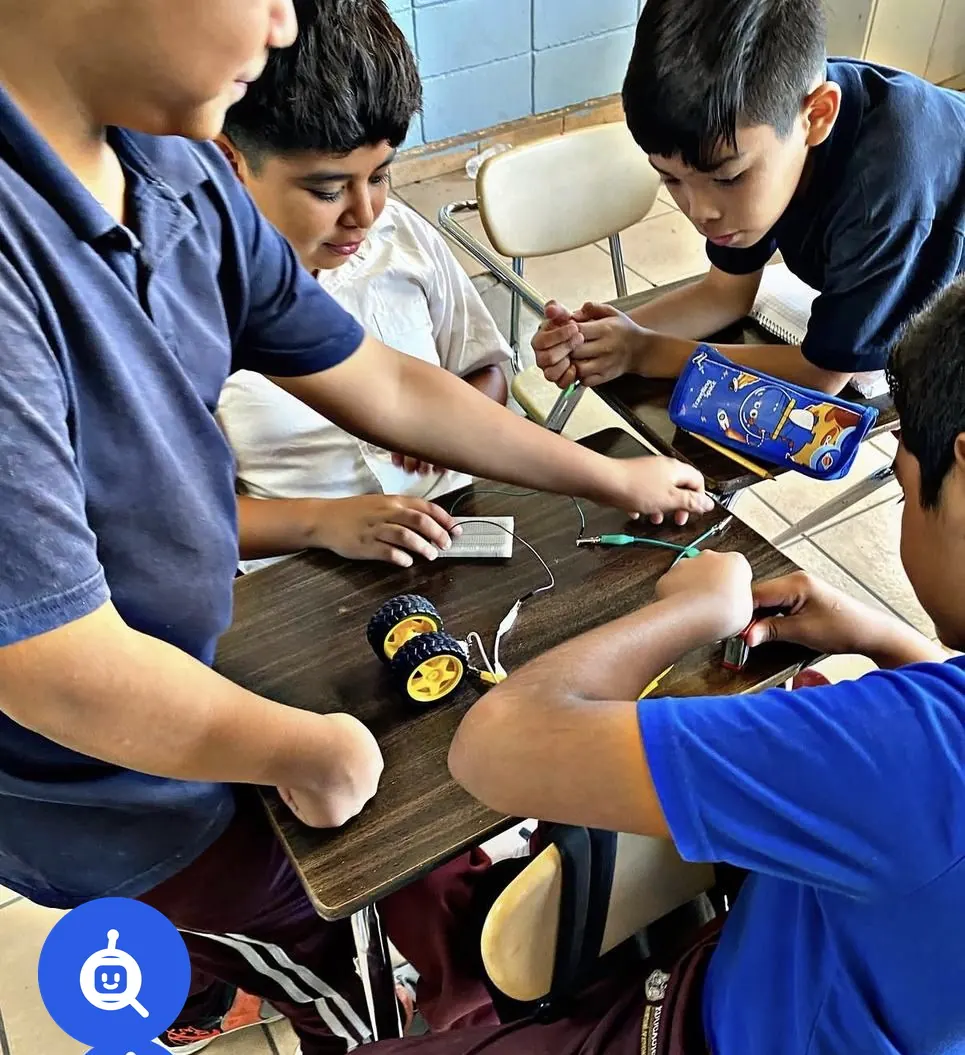 Alumnos de secundaria con uniforme trabajando con motores y ruedas en un taller de robótica en su plantel