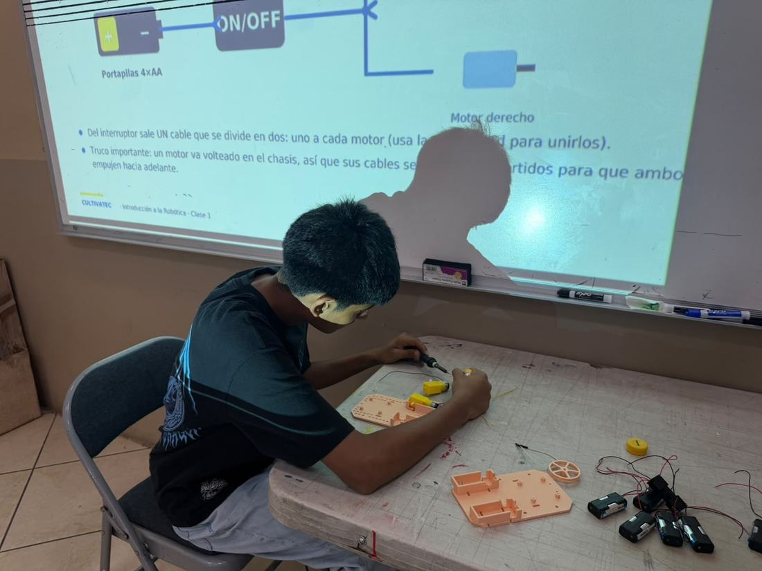 Alumno conecta los motores de su robot siguiendo el diagrama proyectado en la clase de robótica de Qubiko