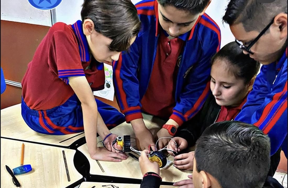 Equipo de alumnos de un colegio armando en conjunto un robot durante el taller de Qubiko
