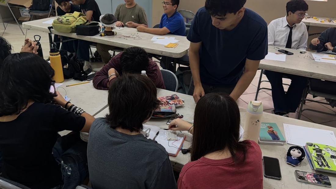 Instructor de Qubiko apoya a un equipo de alumnos que arma su circuito sobre la mesa de trabajo