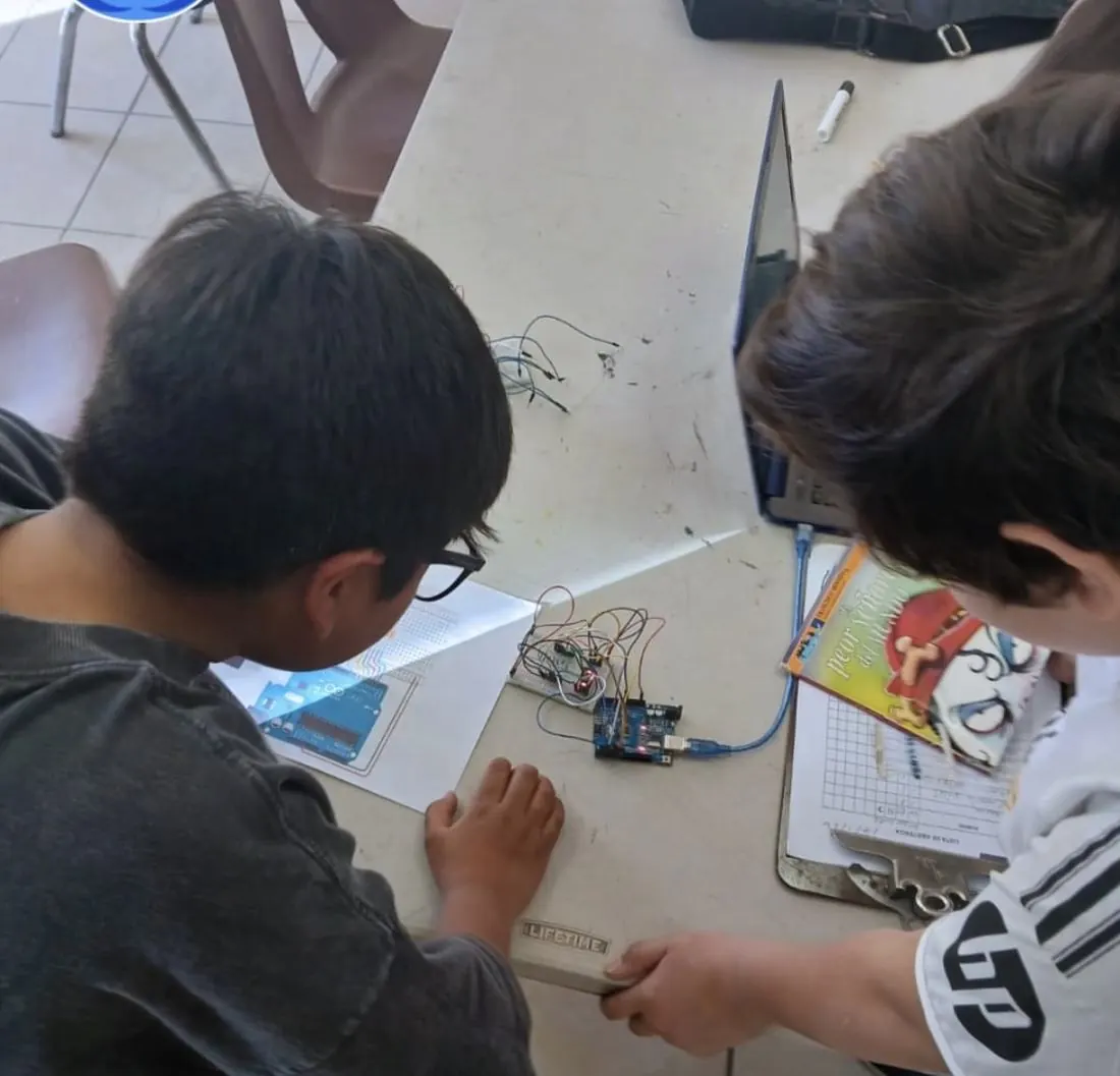 Dos alumnos trabajando en pareja: uno programa en la tablet y el otro conecta la placa del robot
