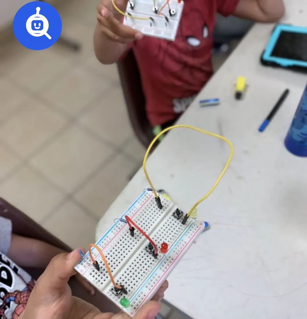 Manos de un alumno sosteniendo una protoboard con un circuito armado en un taller de robótica de Qubiko