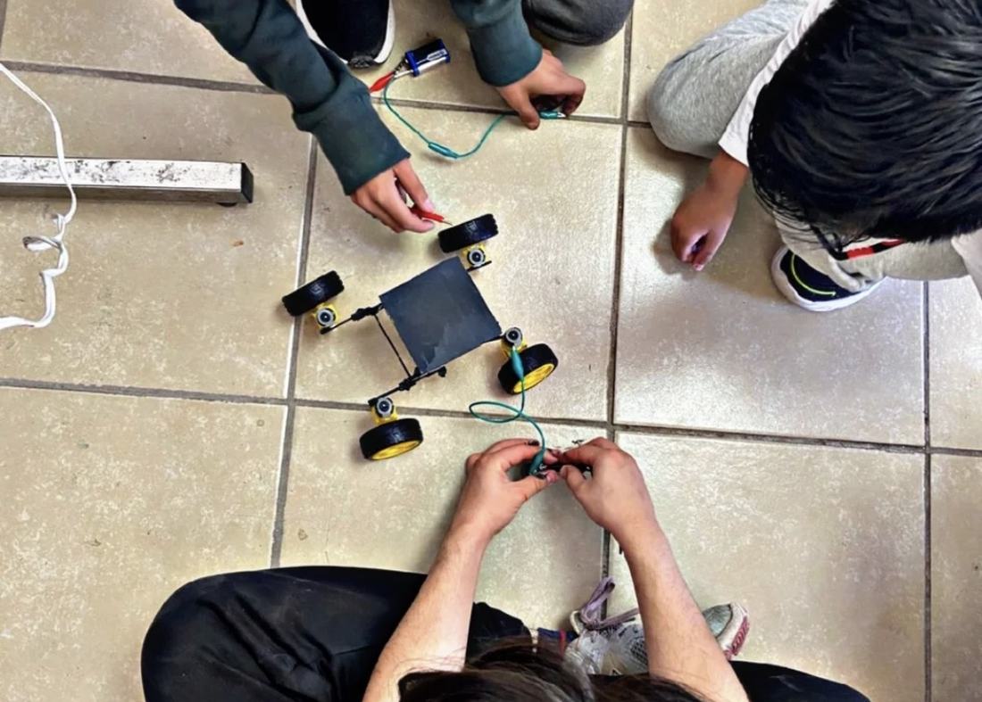 Alumnos probando en el piso el recorrido de un robot móvil armado con el kit de Qubiko